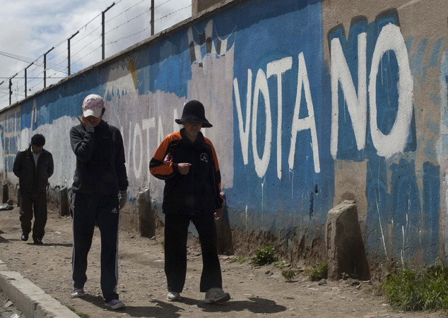 People walks past graffiti that reads in Spanish "Vote no," against President Evo Morales, in El Alto, Bolivia, Saturday, Feb. 20, 2016. Polls indicate voters are about evenly split, with some 15 percent undecided, on Sunday's referendum on whether to amend the constitution so Morales can run in 2019 for a fourth consecutive term. (AP Photo/Juan Karita)